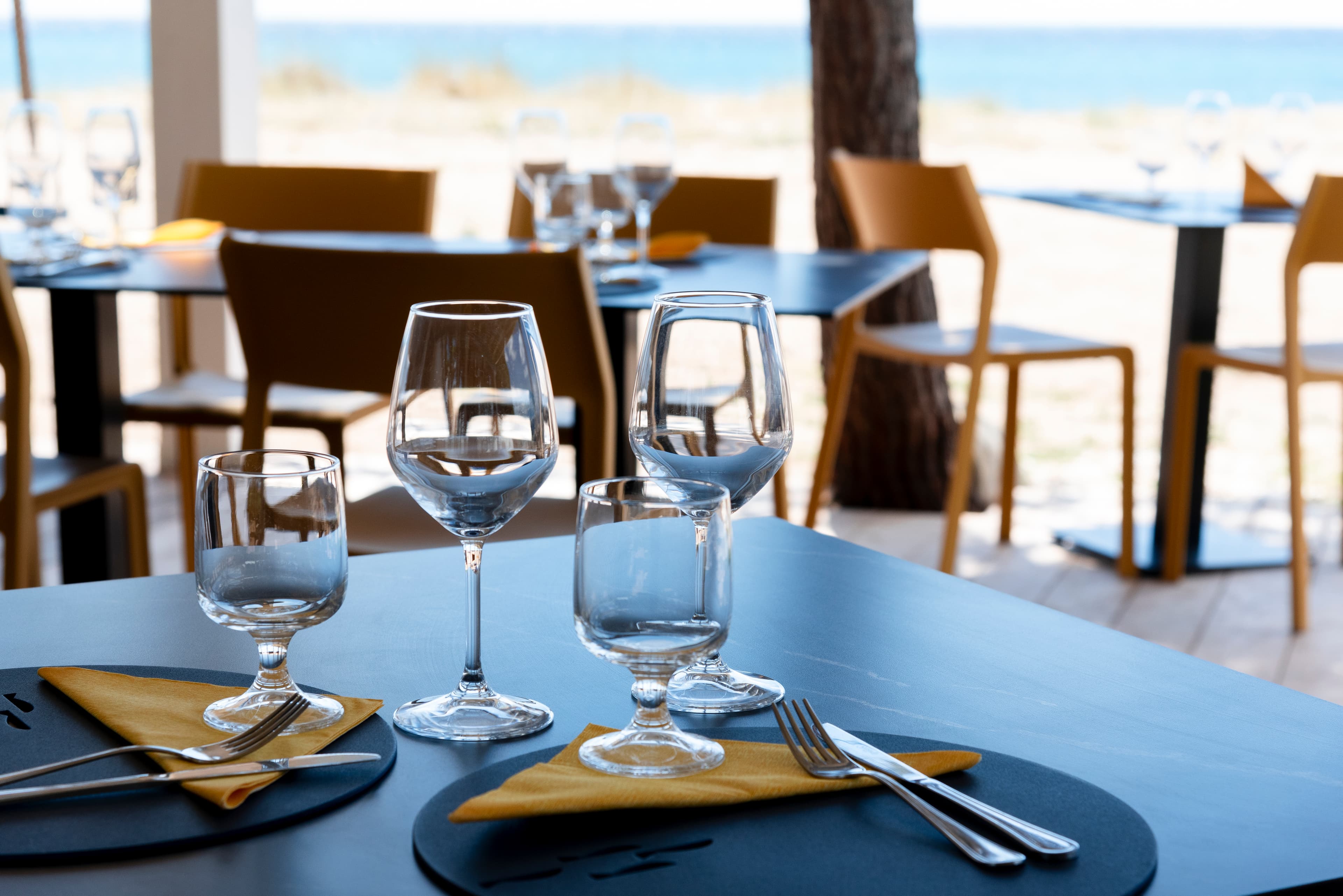 Detalle de una mesa preparada con el mar al fondo.