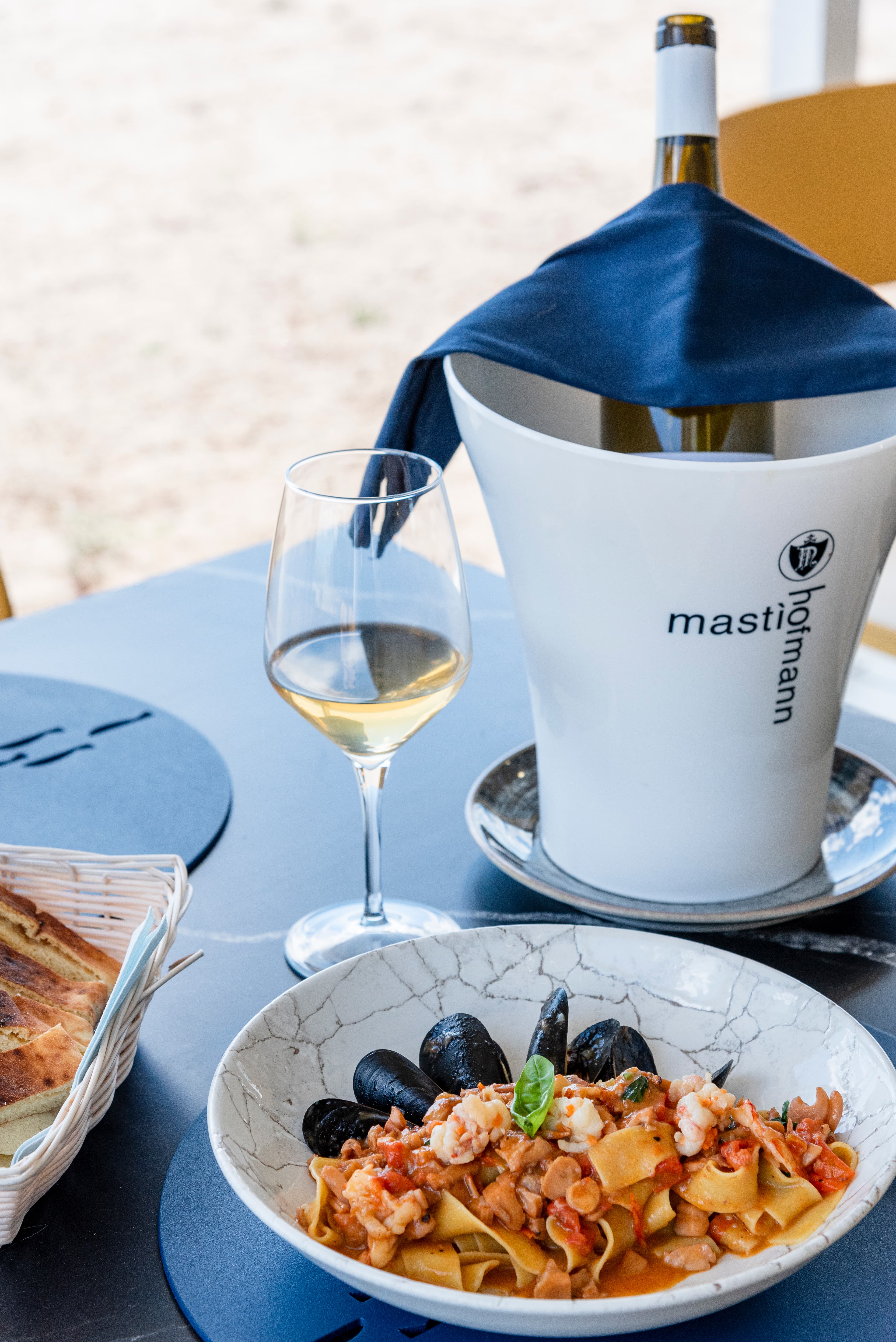 Pasta de Lungomare con pulpo y una copa de vino sobre la mesa.