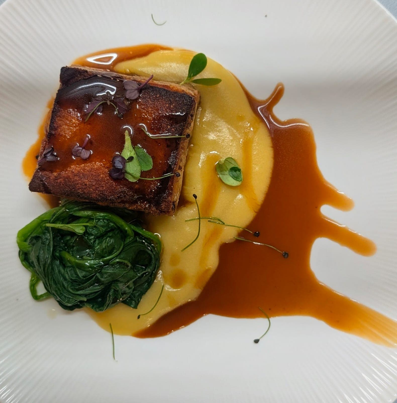 Plato de cochinillo asado servido con patatas al horno.