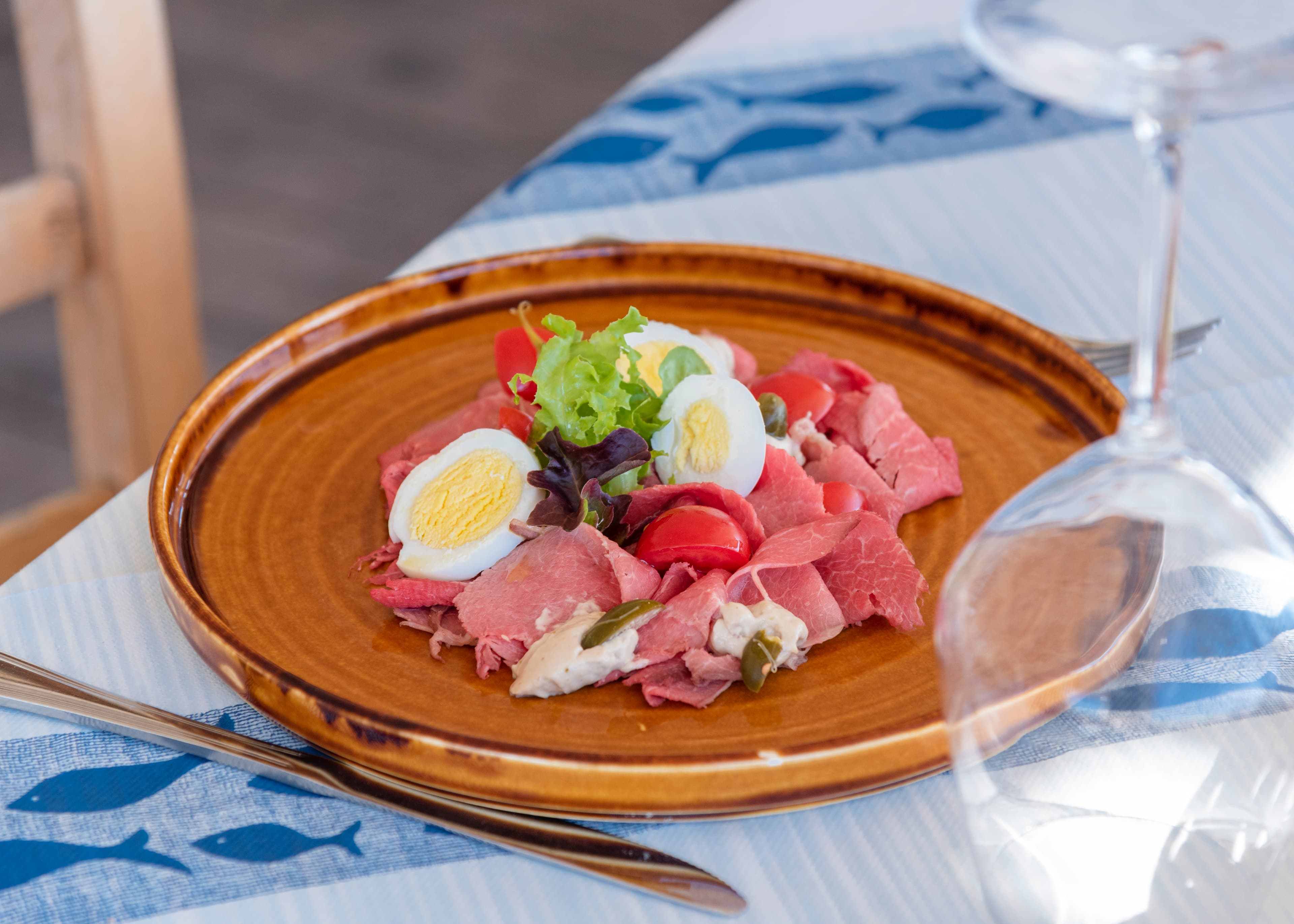 Vitello tonnato emplatado con salsa y guarnicion.